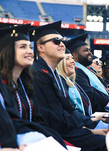 A row of smiling graduates at 2023 commencement